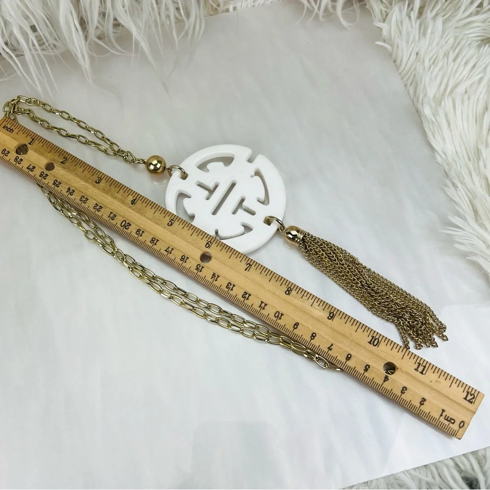 Long, goldtone, costume necklace, with large white pendant, and metal fringe